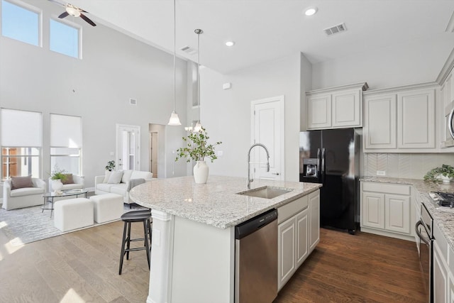 kitchen with dark wood-type flooring, appliances with stainless steel finishes, open floor plan, and a sink