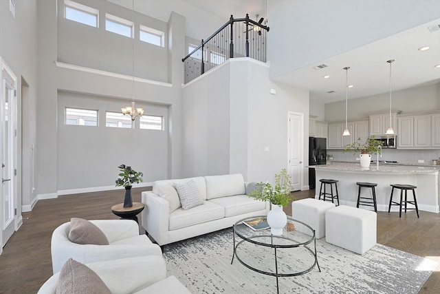 living room with a towering ceiling, dark hardwood / wood-style floors, and an inviting chandelier