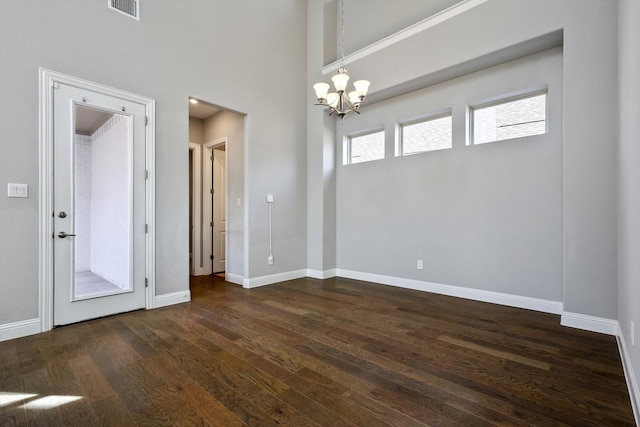 interior space with a towering ceiling, dark wood-type flooring, and a notable chandelier