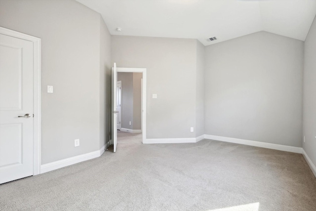 spare room with light carpet and vaulted ceiling