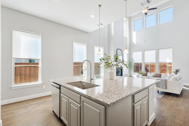 kitchen with ceiling fan, sink, stainless steel dishwasher, a center island with sink, and hardwood / wood-style flooring