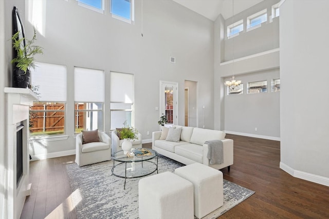 living room with dark hardwood / wood-style floors, a towering ceiling, and an inviting chandelier