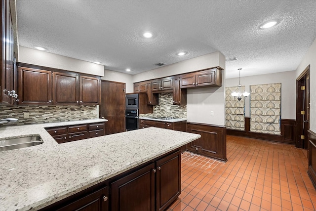 kitchen with backsplash, sink, a chandelier, oven, and hanging light fixtures