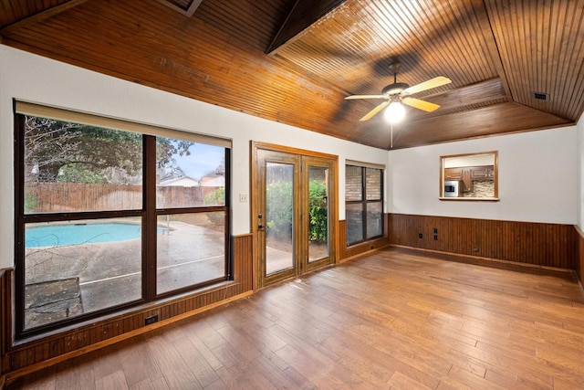 interior space with wooden walls, wooden ceiling, light hardwood / wood-style floors, and ceiling fan