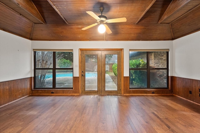 empty room featuring ceiling fan, wood-type flooring, wooden walls, and wooden ceiling