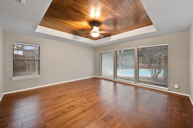 spare room with ceiling fan, a raised ceiling, wood ceiling, and plenty of natural light