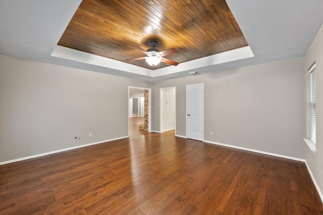 spare room with a tray ceiling, ceiling fan, wooden ceiling, and dark hardwood / wood-style floors