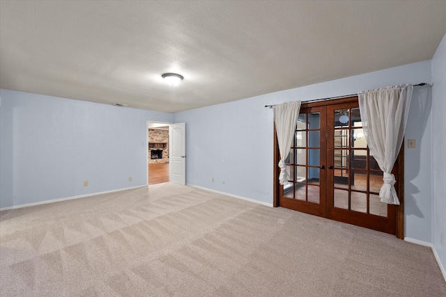 spare room with a textured ceiling, light carpet, and french doors