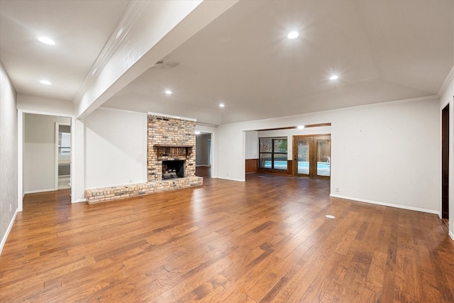 unfurnished living room with hardwood / wood-style flooring, crown molding, a fireplace, and french doors