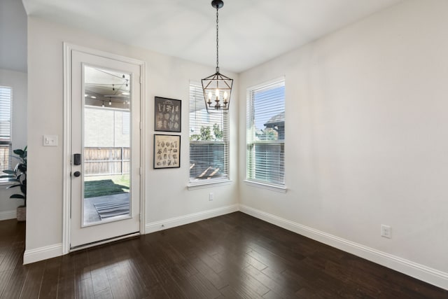 unfurnished dining area featuring a chandelier and dark hardwood / wood-style floors