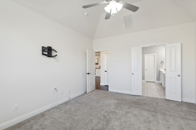 unfurnished bedroom featuring ensuite bath, ceiling fan, high vaulted ceiling, and light colored carpet