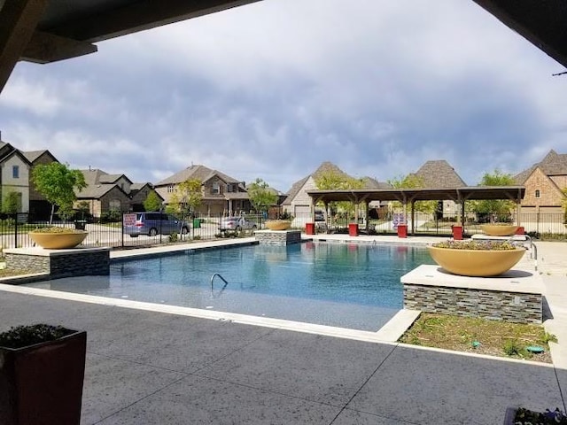 community pool with a gazebo, a patio area, fence, and a residential view