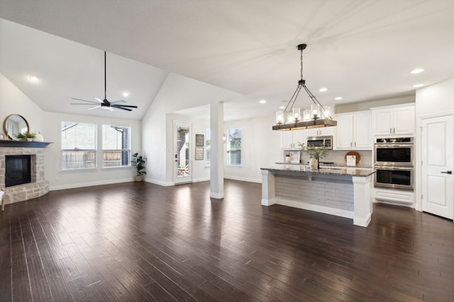 kitchen featuring dark hardwood / wood-style floors, a center island with sink, stainless steel appliances, and stone countertops