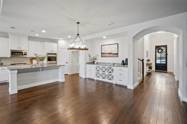 kitchen featuring light stone counters, appliances with stainless steel finishes, decorative light fixtures, and white cabinets