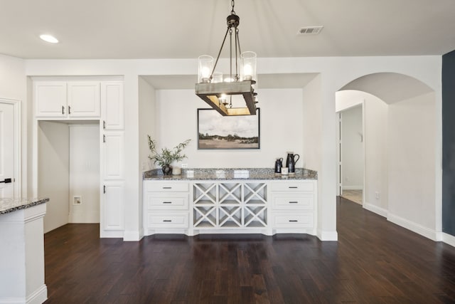 kitchen featuring pendant lighting, dark hardwood / wood-style flooring, light stone countertops, and white cabinets