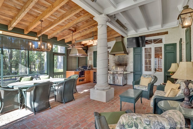 sunroom / solarium featuring beamed ceiling, decorative columns, and beverage cooler