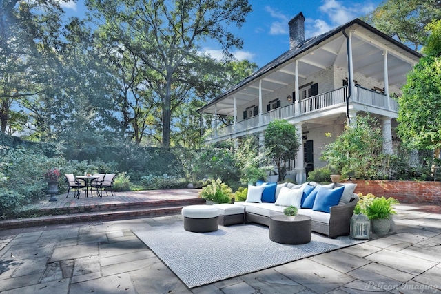 back of house with an outdoor living space, a balcony, and a patio area