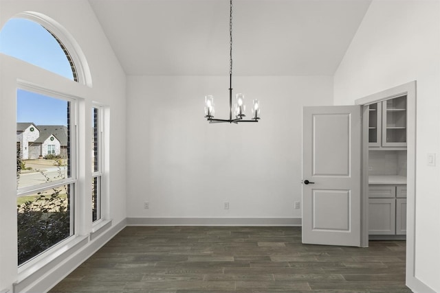 unfurnished dining area featuring vaulted ceiling, dark hardwood / wood-style floors, and an inviting chandelier