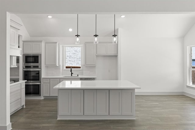 kitchen featuring hanging light fixtures, vaulted ceiling, a center island, and tasteful backsplash