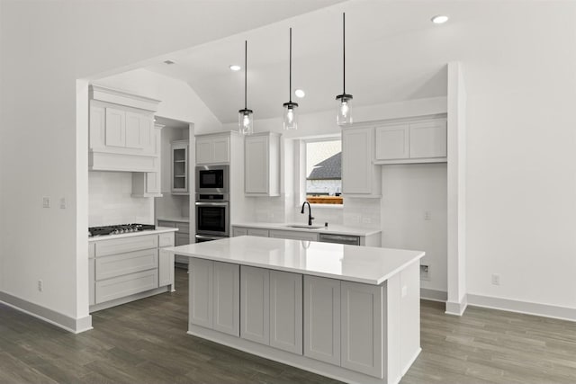 kitchen featuring stainless steel appliances, lofted ceiling, hanging light fixtures, a kitchen island, and sink