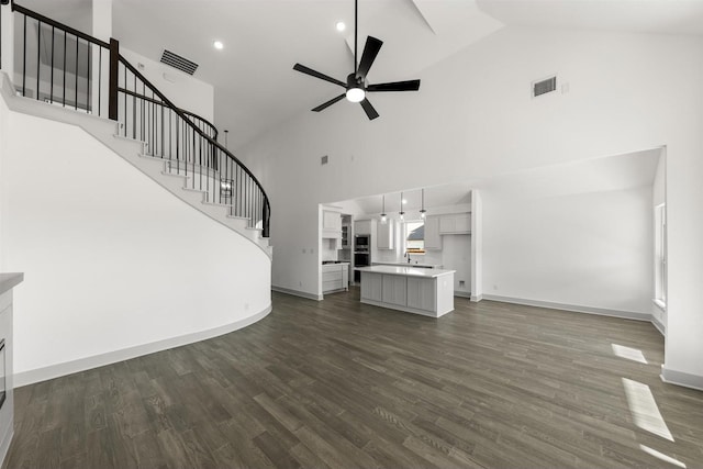 unfurnished living room featuring ceiling fan, dark wood-type flooring, and high vaulted ceiling