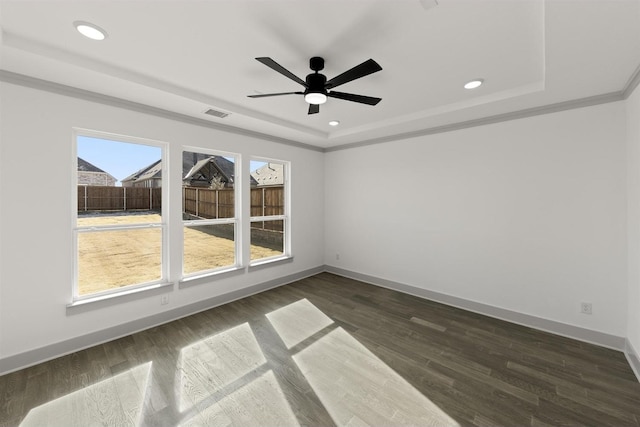 empty room featuring ceiling fan, dark wood-type flooring, a tray ceiling, and crown molding