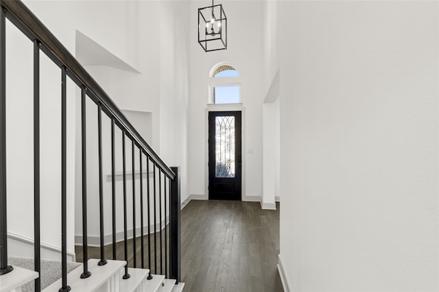 entrance foyer featuring dark wood-type flooring, a chandelier, and a towering ceiling