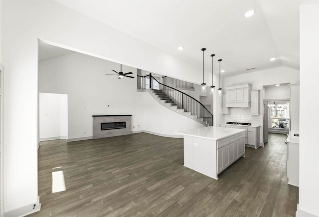 kitchen featuring ceiling fan with notable chandelier, a kitchen island, tasteful backsplash, hanging light fixtures, and dark hardwood / wood-style floors