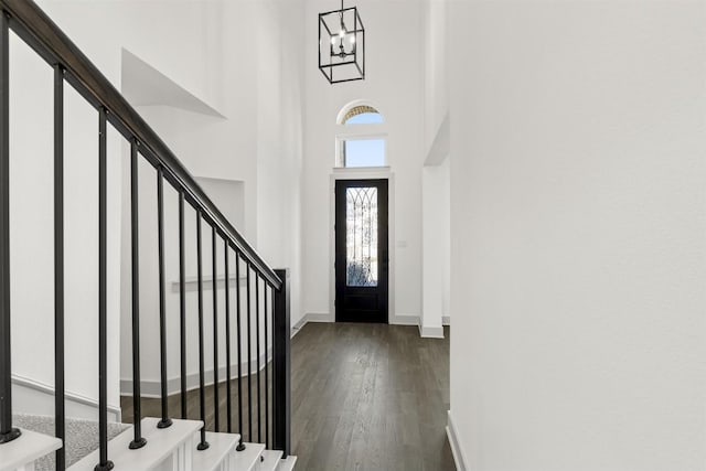 foyer with dark hardwood / wood-style flooring, a high ceiling, and a notable chandelier