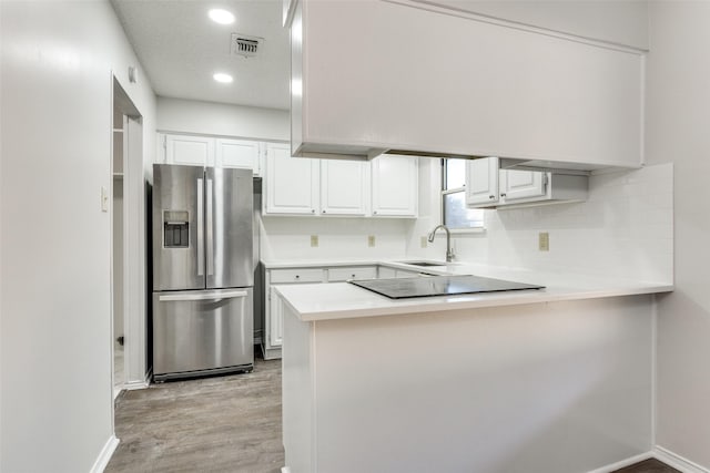 kitchen with sink, stainless steel refrigerator with ice dispenser, kitchen peninsula, white cabinets, and light wood-type flooring