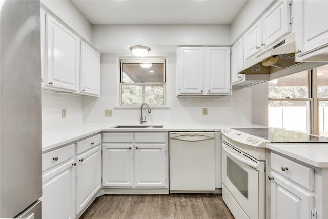 kitchen featuring white appliances, premium range hood, white cabinets, sink, and wood-type flooring