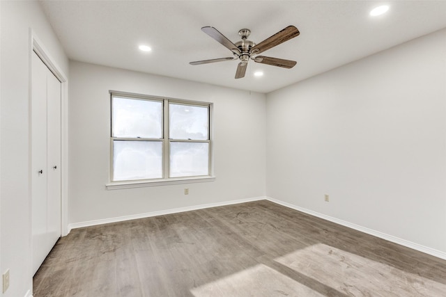 unfurnished bedroom featuring hardwood / wood-style floors, a closet, and ceiling fan