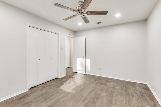 unfurnished bedroom featuring light wood-type flooring, a closet, and ceiling fan