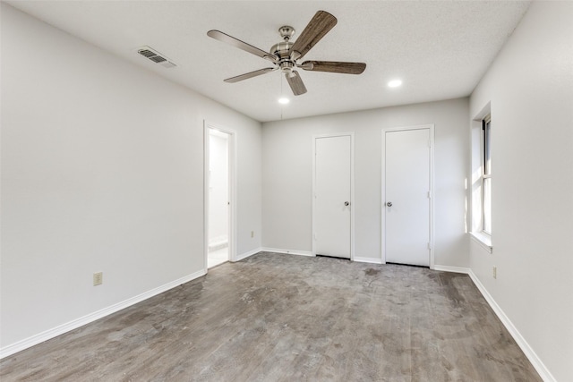 unfurnished bedroom featuring a textured ceiling, ceiling fan, light hardwood / wood-style flooring, and two closets