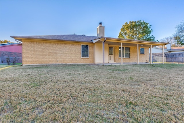 rear view of property featuring a patio area and a lawn