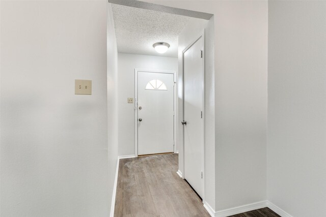 doorway featuring light hardwood / wood-style floors and a textured ceiling