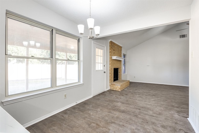 unfurnished living room with a brick fireplace, a textured ceiling, vaulted ceiling, a notable chandelier, and dark hardwood / wood-style floors