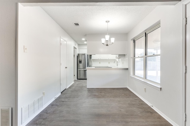 kitchen with white cabinetry, stainless steel fridge with ice dispenser, dark hardwood / wood-style floors, kitchen peninsula, and decorative light fixtures