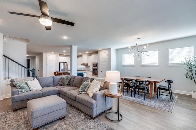 living room featuring hardwood / wood-style floors, ceiling fan with notable chandelier, and plenty of natural light