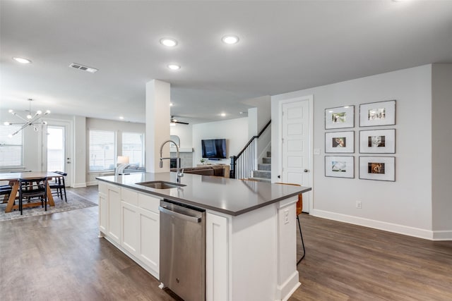 kitchen with stainless steel dishwasher, dark wood-type flooring, sink, a center island with sink, and white cabinetry