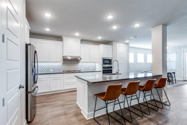 kitchen with sink, a breakfast bar area, light hardwood / wood-style floors, white cabinetry, and stainless steel appliances