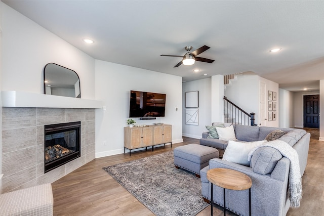 living room featuring a fireplace, hardwood / wood-style floors, and ceiling fan