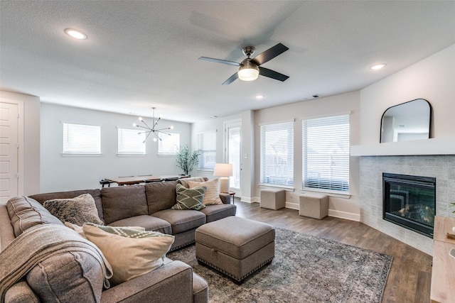 living room featuring ceiling fan with notable chandelier, wood-type flooring, and a textured ceiling