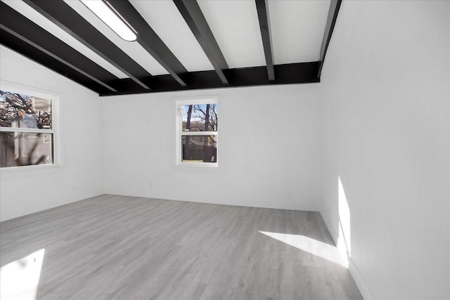 unfurnished room with vaulted ceiling with beams and light hardwood / wood-style floors