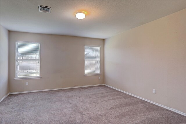 carpeted empty room with a textured ceiling