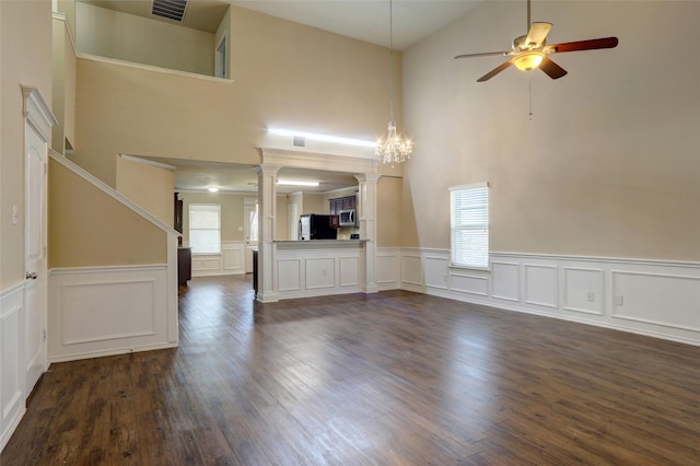 unfurnished living room with dark hardwood / wood-style flooring, decorative columns, and ceiling fan