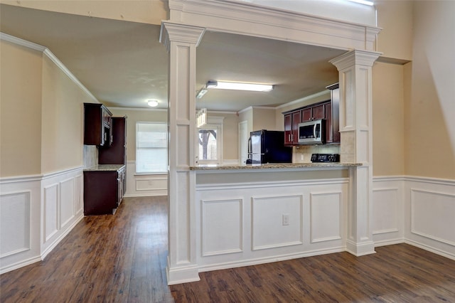 kitchen featuring light stone countertops, dark wood-type flooring, decorative columns, and black fridge