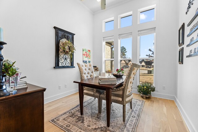 dining area featuring a high ceiling, light hardwood / wood-style flooring, ceiling fan, and ornamental molding