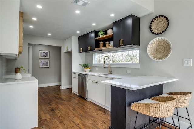 kitchen featuring dishwasher, kitchen peninsula, a breakfast bar, dark hardwood / wood-style flooring, and sink