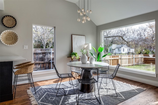 dining room with lofted ceiling, a notable chandelier, and hardwood / wood-style floors